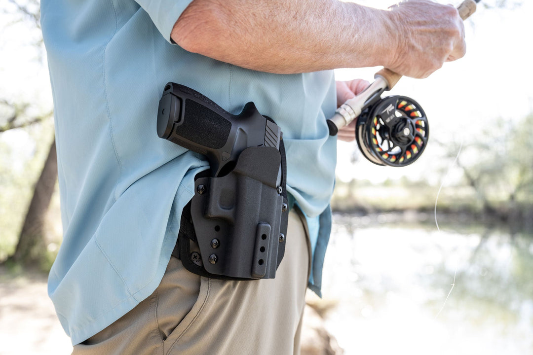 omnicarry owb holster on the hip of a man fishing on a lake sig p320 in holster