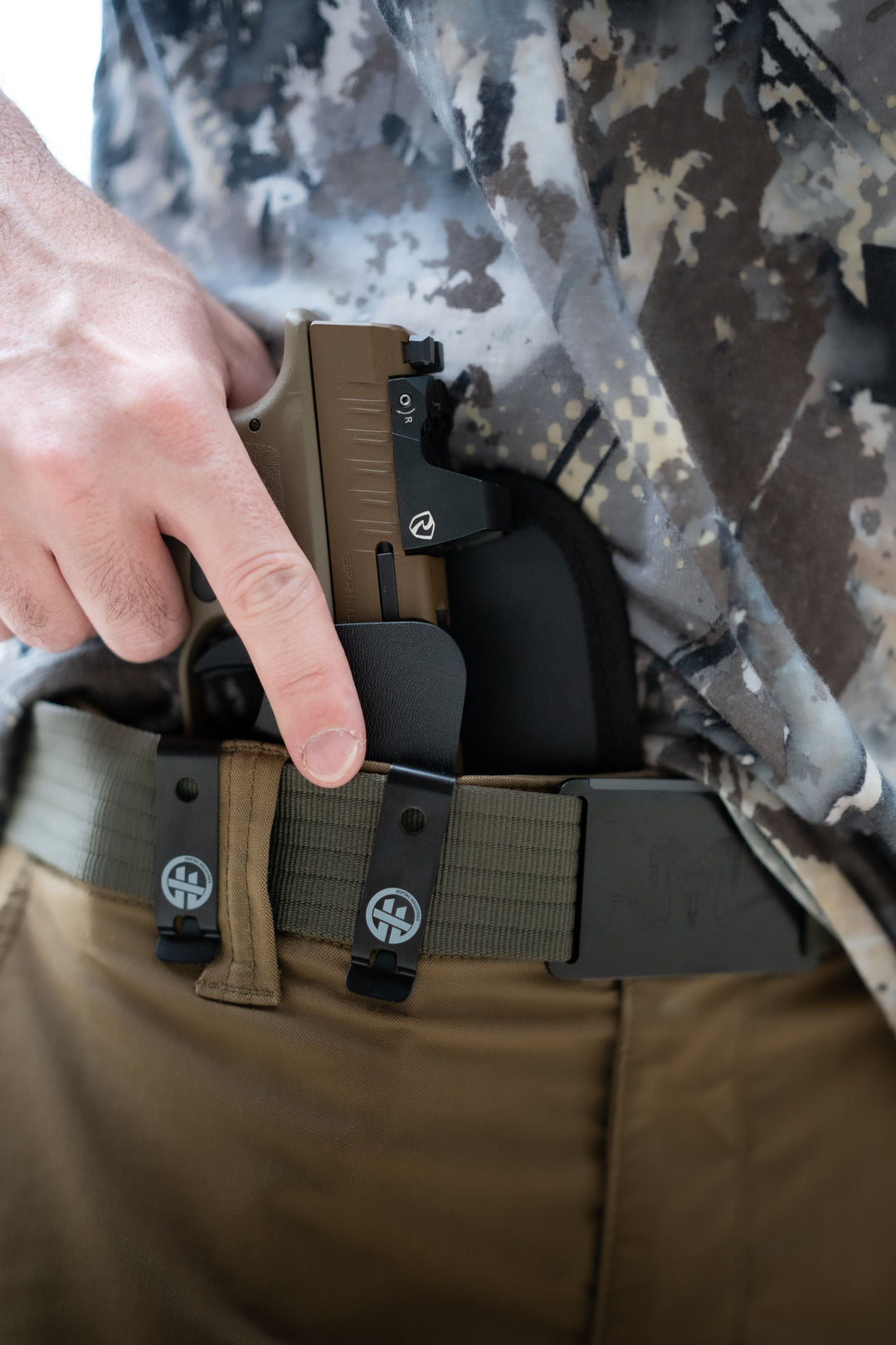 Person drawing a concealed pistol from an OMNICARRY IWB holster, demonstrating safe and proper holster draw technique